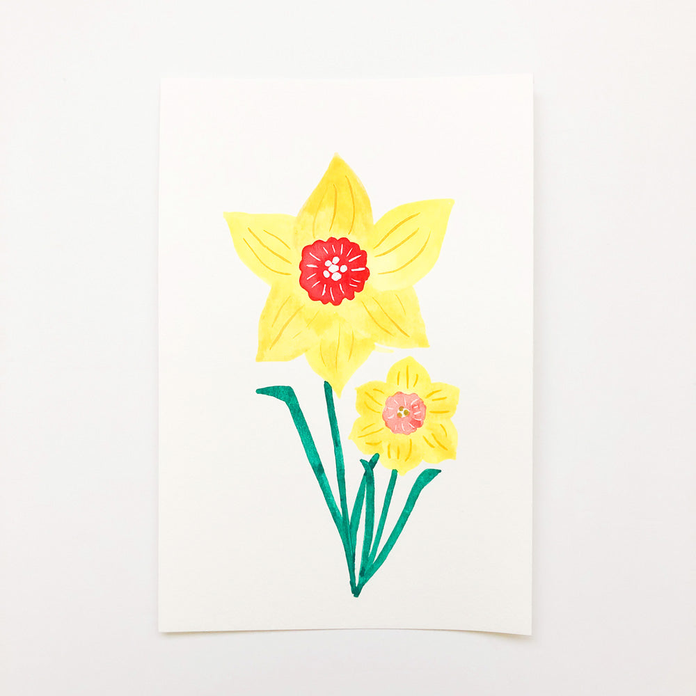 Watercolor painting of two daffodils with bright yellow petals and vibrant red and pink centers, set against a white background. The larger flower is prominently featured above a smaller bloom, both with green stems.