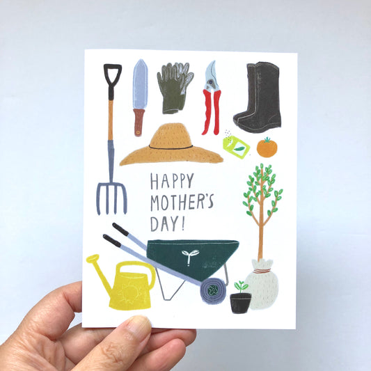 Mother's Day card featuring gardening tools and accessories including a pitchfork, trowel, gloves, pruning shears, boots, sun hat, wheelbarrow, watering can, seedling, and small potted plant, with "Happy Mother's Day!" text in the center