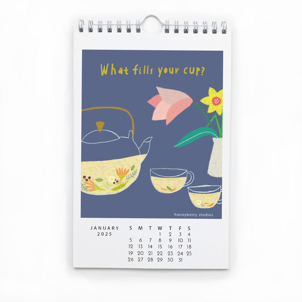 2025 wall calendar page for January featuring colorful illustration of teapot, cups, flower, and butterfly on blue background with "What fills your cup?" text and monthly date grid