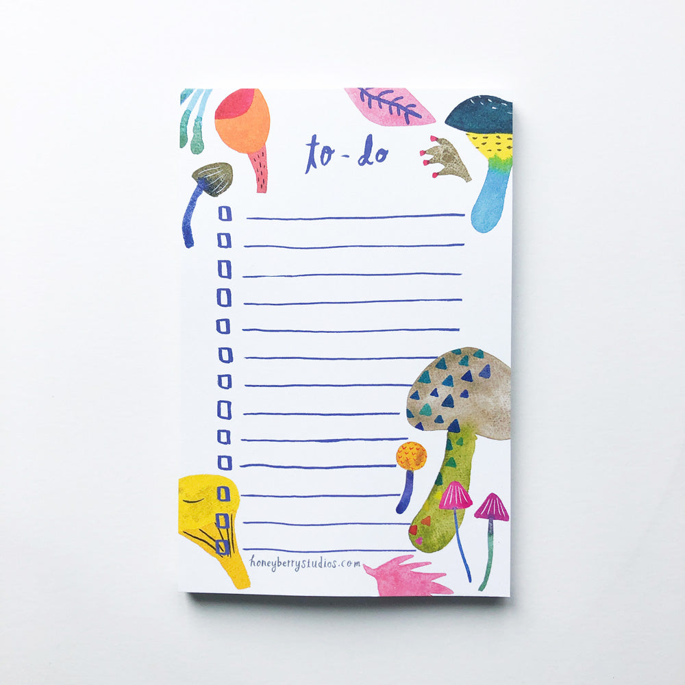 Colorful mushroom-themed to-do list notepad with watercolor illustrations, blank lines for tasks, and whimsical forest elements like leaves and fungi in vibrant hues