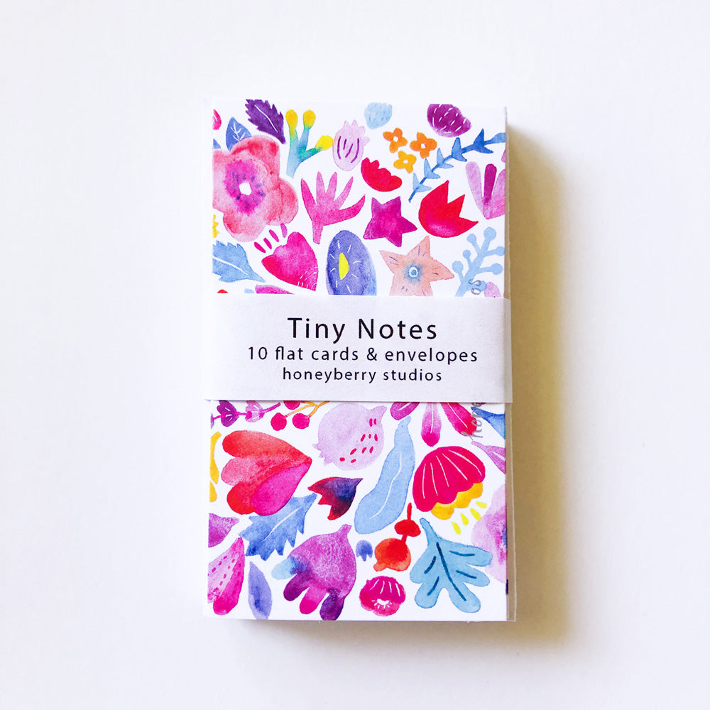 Colorful watercolor floral design on tiny note cards set, featuring vibrant red, pink, purple, and blue flowers and leaves, with a white band displaying "Tiny Notes" and product details