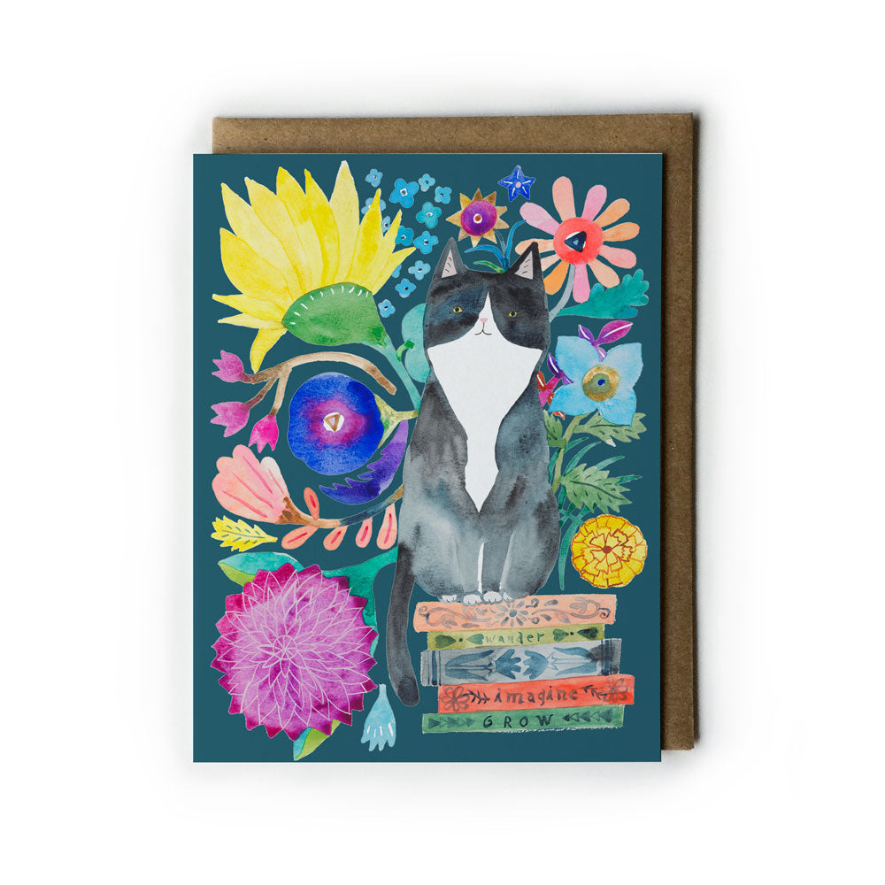 Colorful watercolor greeting card featuring a tuxedo cat sitting on books, surrounded by vibrant flowers and whimsical elements on a teal background, with a kraft envelope