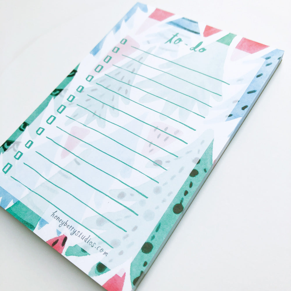 Christmas-themed to-do list notepad with watercolor forest illustrations, featuring green lines for tasks and colorful tree designs around the edges, perfect for holiday planning and organization