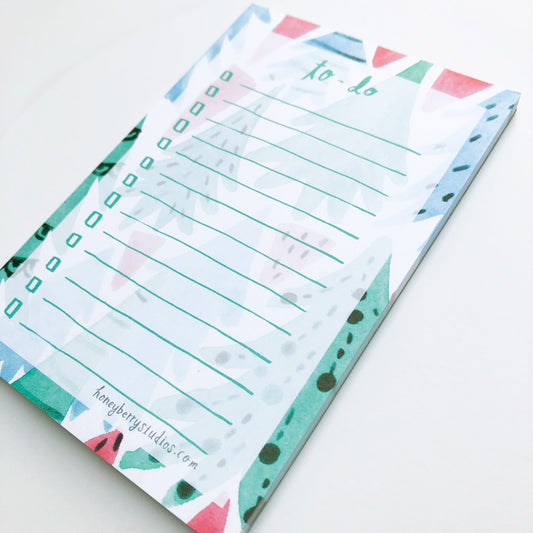 Christmas-themed to-do list notepad with watercolor forest illustrations, featuring green lines for tasks and colorful tree designs around the edges, perfect for holiday planning and organization