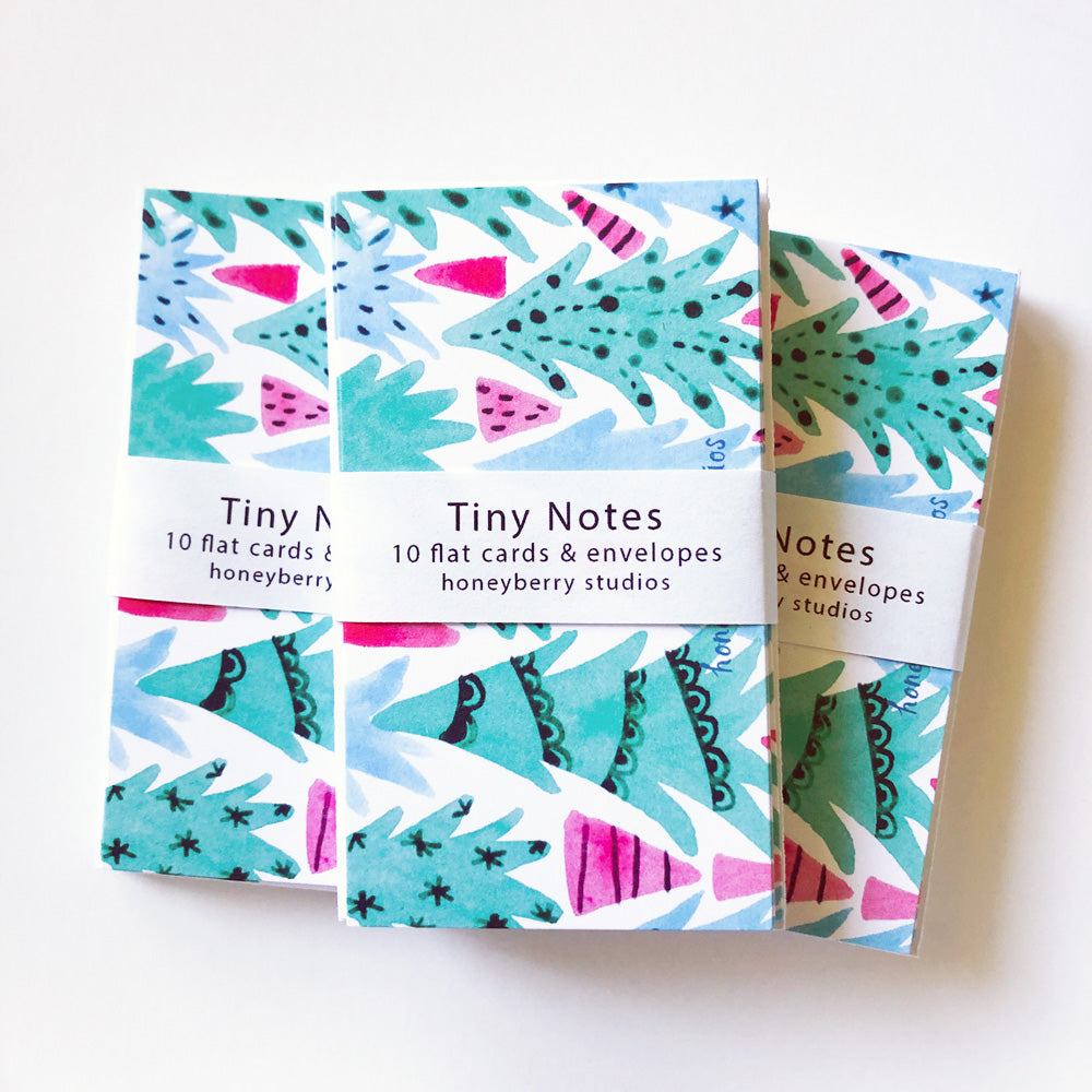 Colorful set of Tiny Notes featuring whimsical abstract Christmas tree designs in teal, pink, and blue. Three stacks of cards with decorative wrap-around bands displaying product information from Honeyberry Studios.