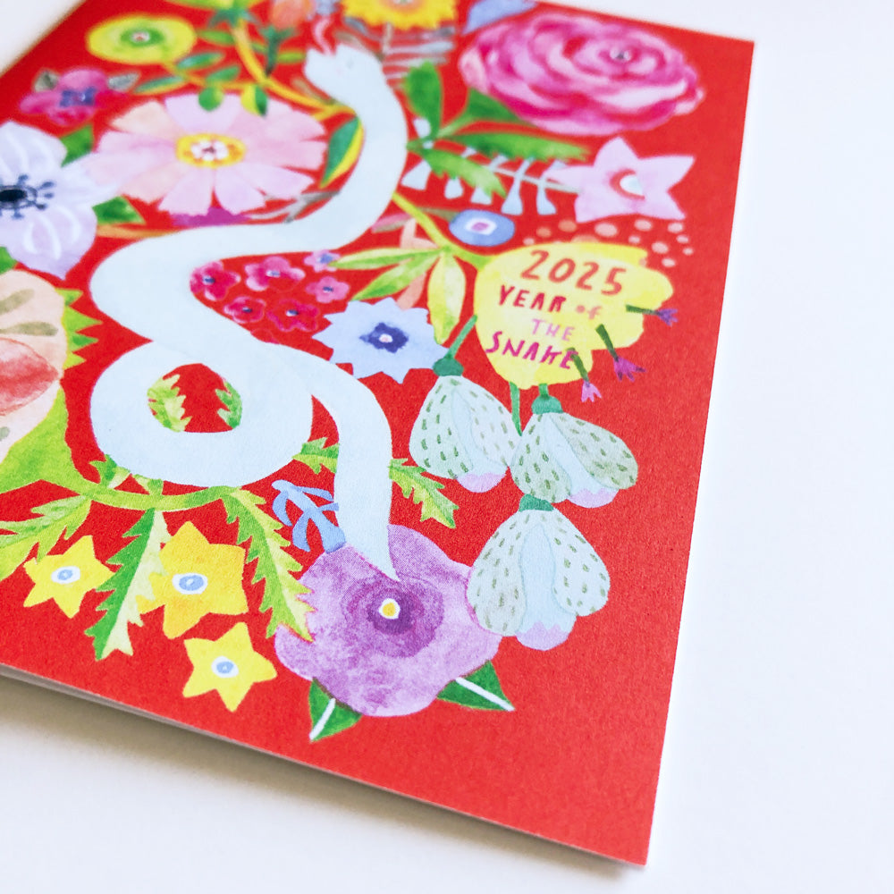 Vibrant 2025 Year of the Snake holiday card featuring colorful floral design with white snake, roses, and various flowers on red background