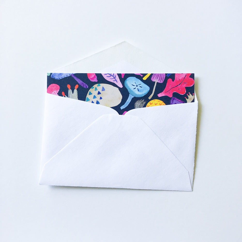 Colorful watercolor mushroom illustration peeking out of a white envelope, showcasing vibrant tiny note card for Shopify product "Colorful Mushrooms Tiny Notes Set