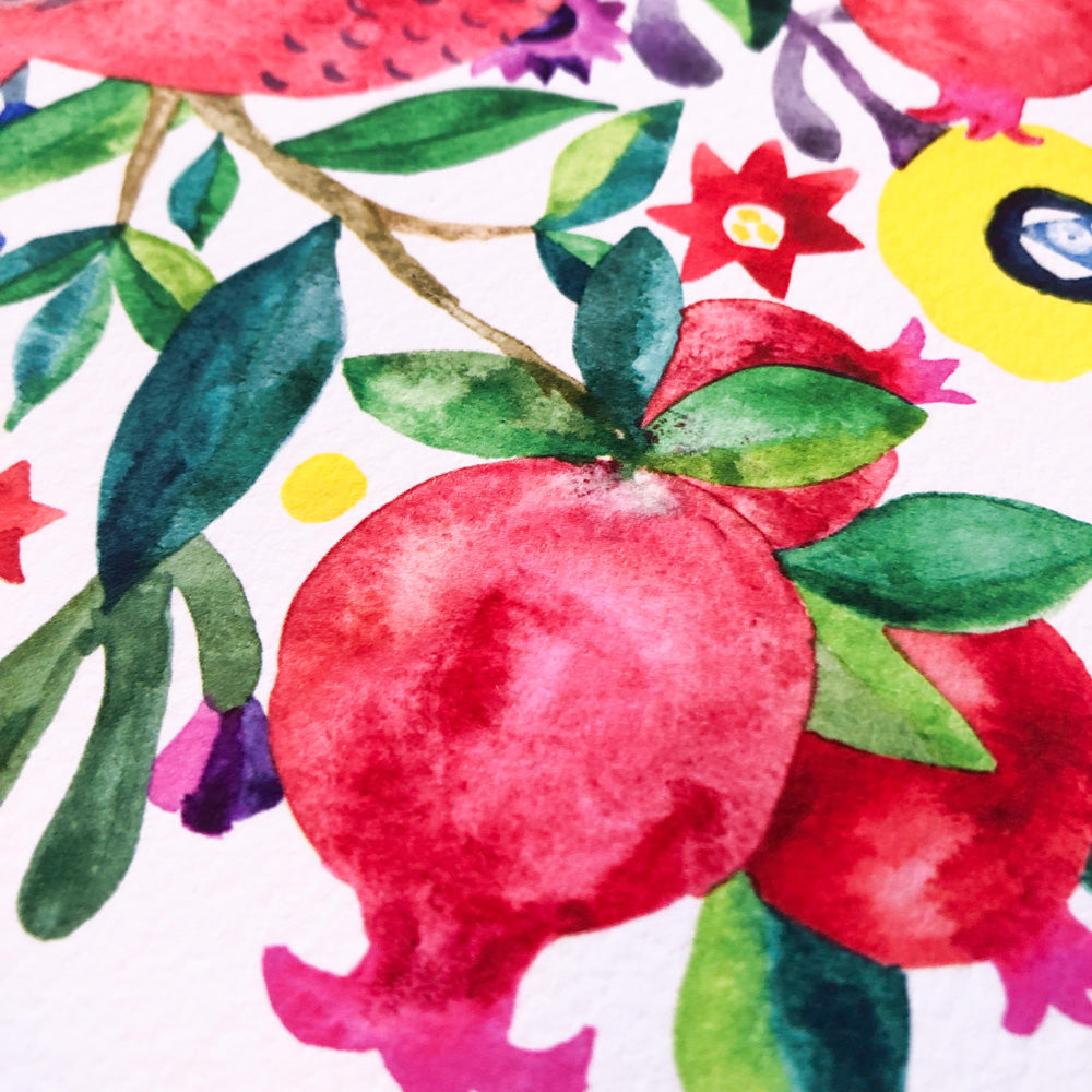 Vibrant watercolor painting featuring a red pomegranate with green leaves, surrounded by colorful flowers and foliage. Close-up view showcasing the artwork's texture and detail on white paper.