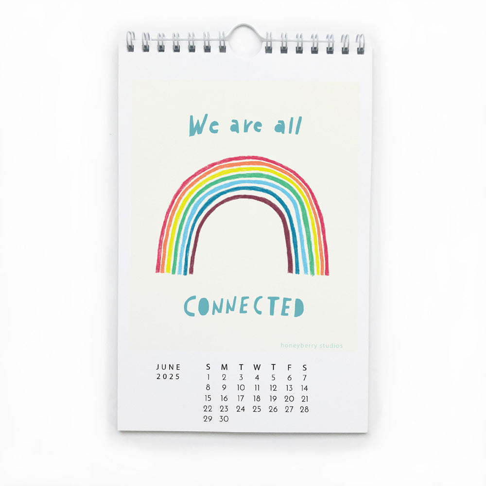 2025 wall calendar page for June featuring colorful rainbow illustration with text "We are all connected" and monthly date grid, spiral-bound at top with metal hanger