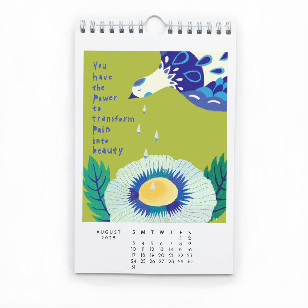 Colorful wall calendar page for August 2025 featuring whimsical illustration of stylized flower and horse with inspirational quote about transforming pain into beauty on green background