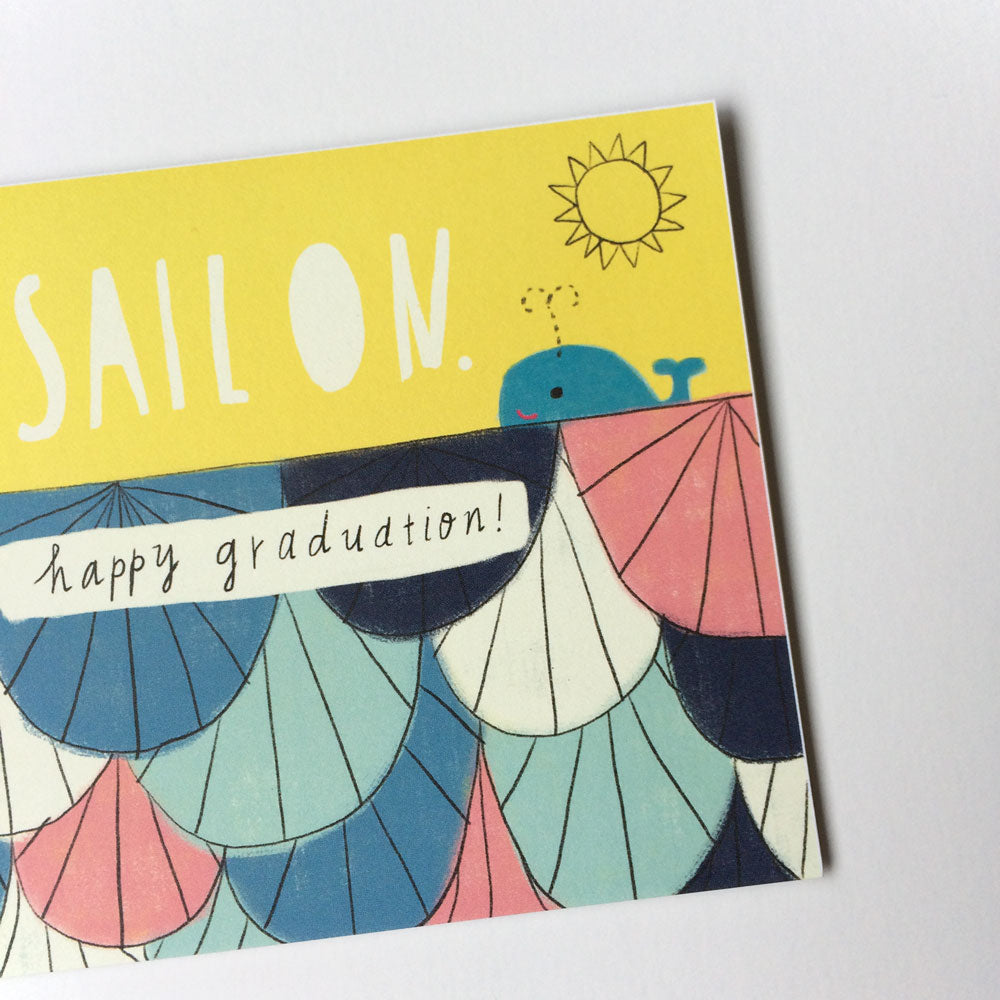 Colorful graduation card featuring a whimsical sailboat design with waves, a smiling whale, and a bright sun. Text reads "SAIL ON" and "happy graduation!" in handwritten style. Card has a cheerful, nautical theme perfect for celebrating new graduates.