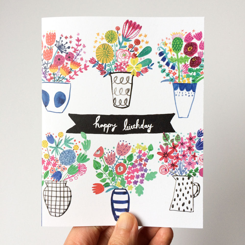 Colorful illustrated birthday card featuring six vibrant floral bouquets in various vases and containers, with a central black banner reading "happy birthday" in white script text